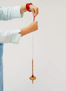 person drafting fibers with a drop spindle